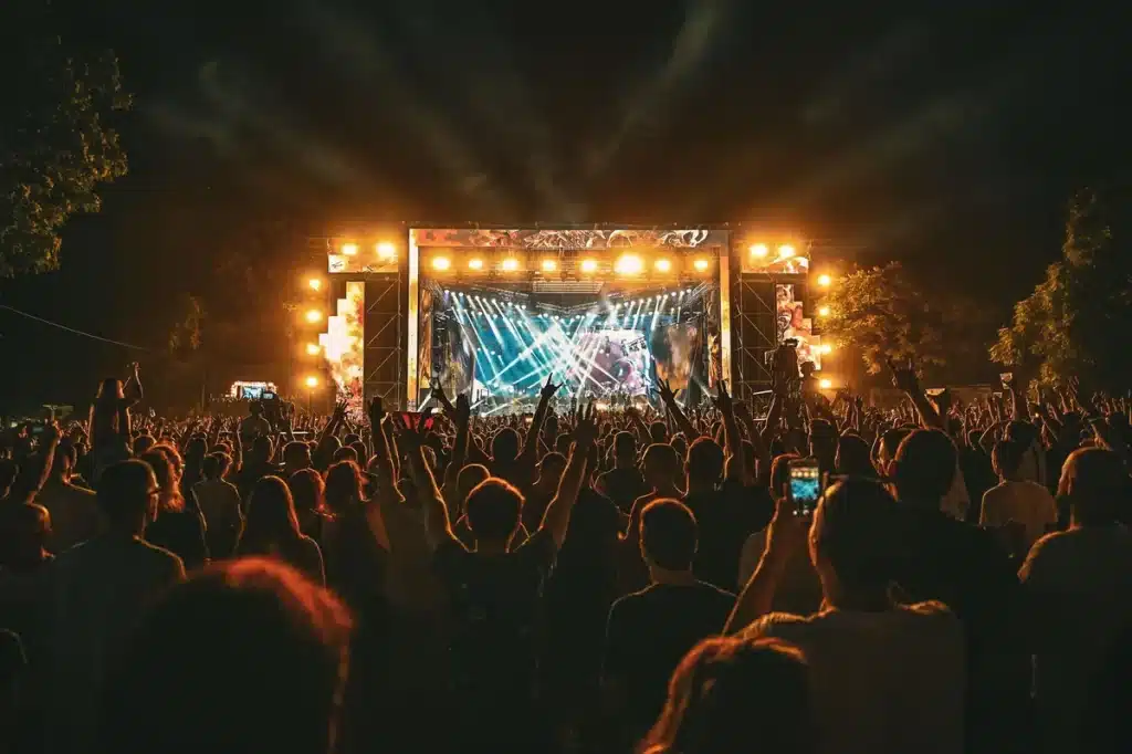Multitud de personas disfrutando de un festival de música con luces de escenario de colores
