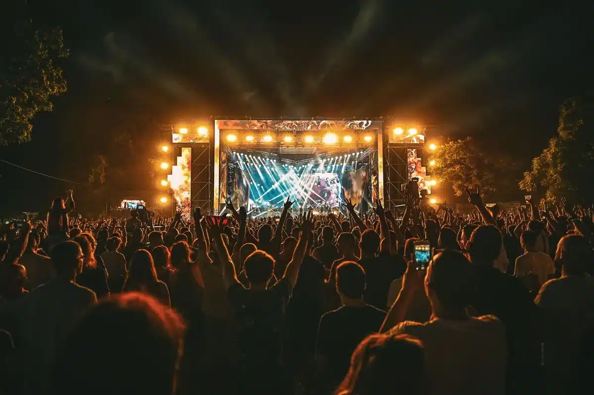 Multitud de personas disfrutando de un festival de música con luces de escenario de colores