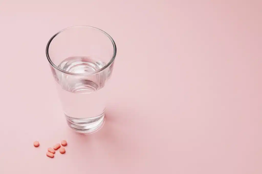 Tableta de medicamento para pérdida de peso junto a un vaso de agua y alimentos saludables