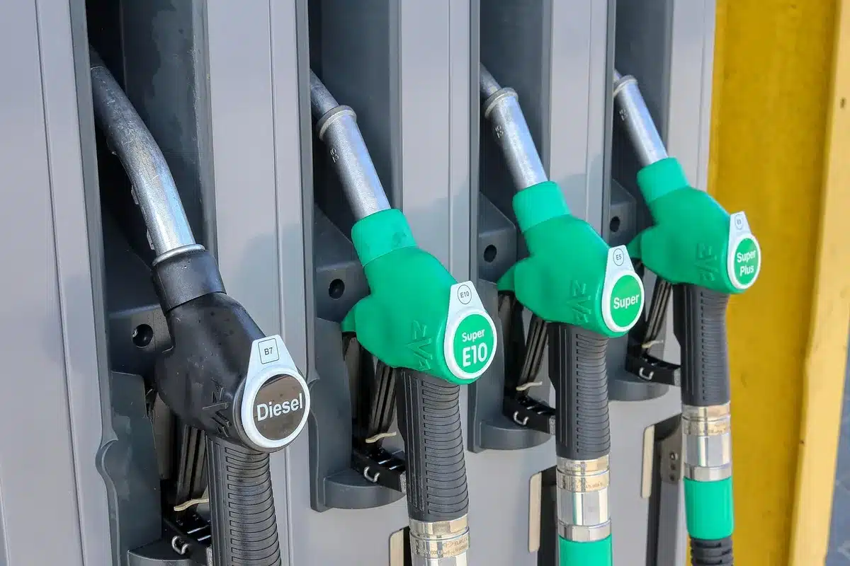 Medidor de combustible y surtidor de gasolina junto a un coche