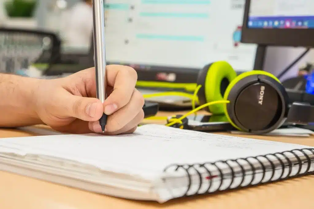 Manos anónimas trabajando con una laptop y notas en un escritorio de oficina