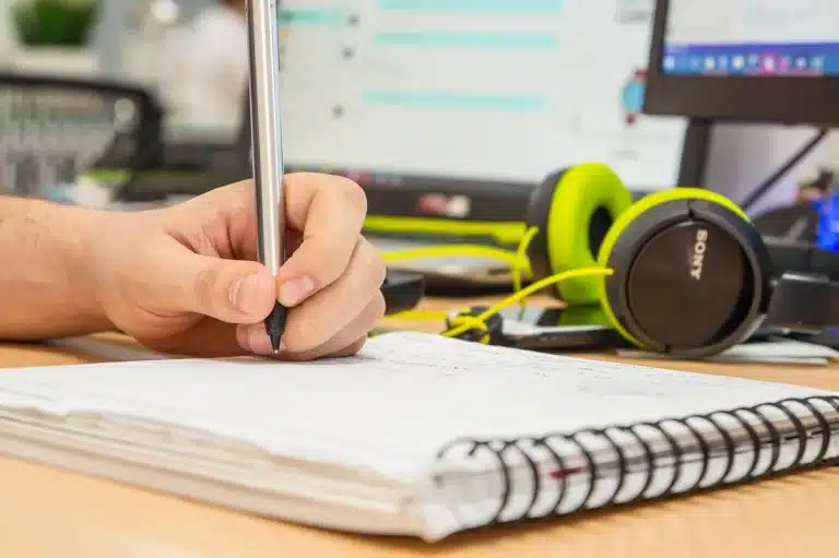 Manos anónimas trabajando con una laptop y notas en un escritorio de oficina