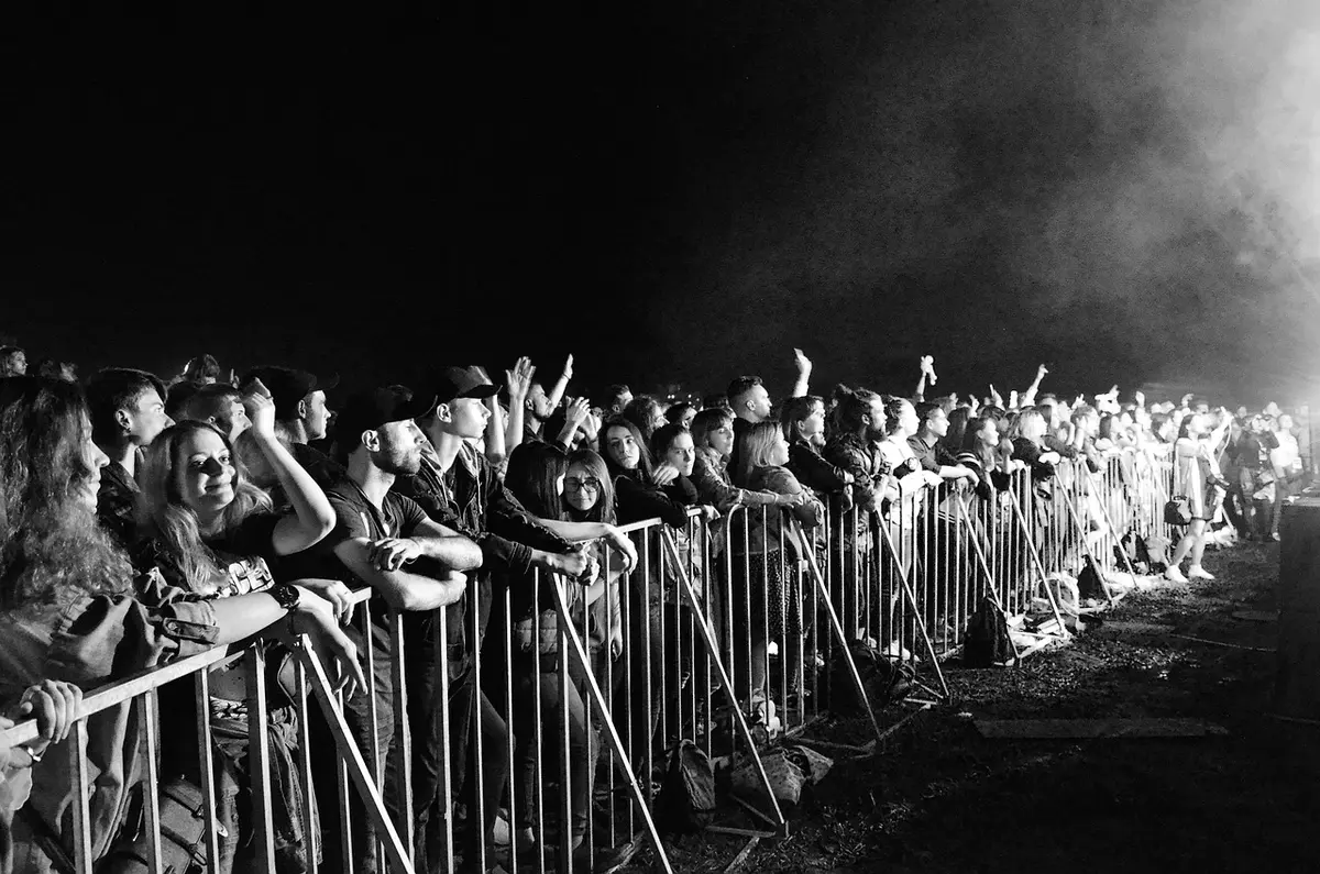 Público anónimo en un concierto de rock con manos levantadas y luces de escenario