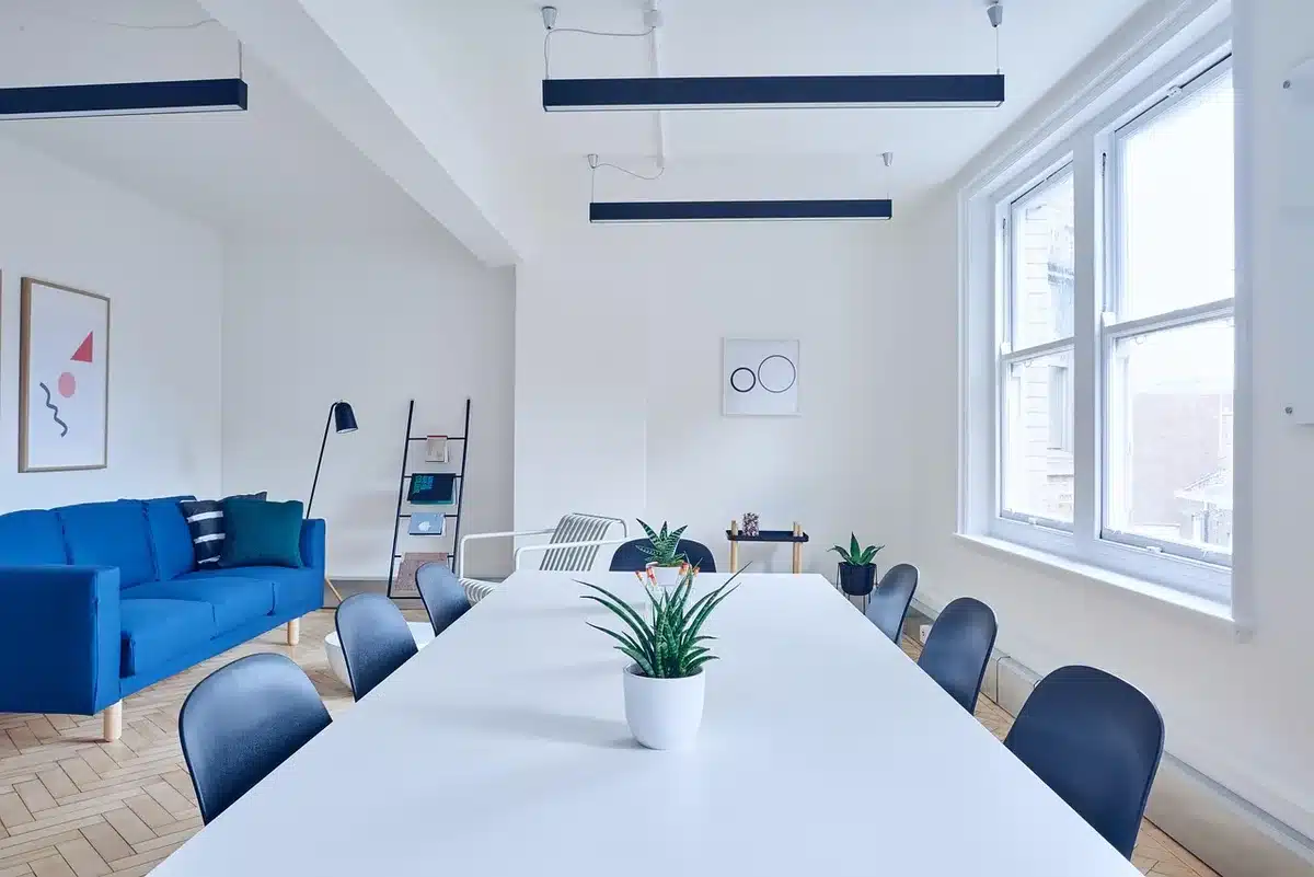 An empty modern office meeting table with a closed laptop, a notebook, and an anonymous coffee cup; sunlight across the tabletop suggests early planning — no logos or identifiable people