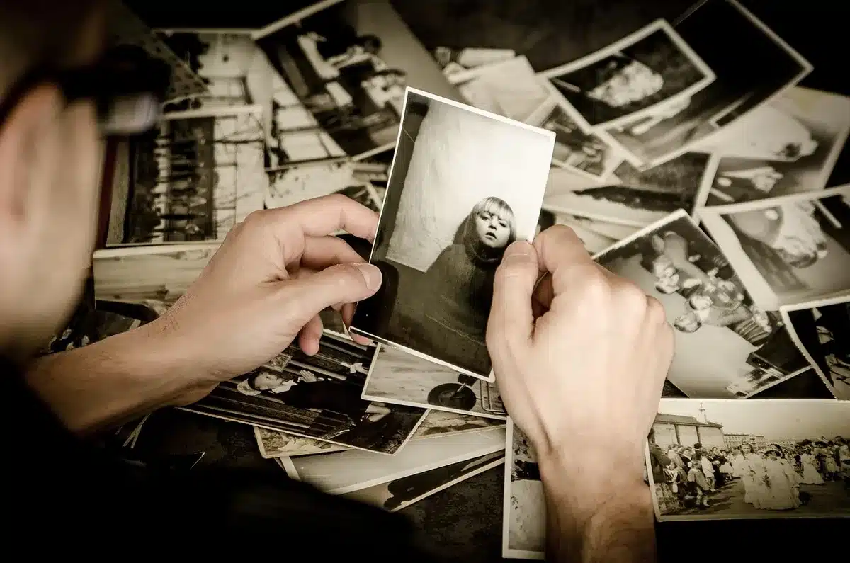 An anonymous pair of hands holding a smartphone showing a blurred photo grid, with a translucent overlay suggesting image analysis