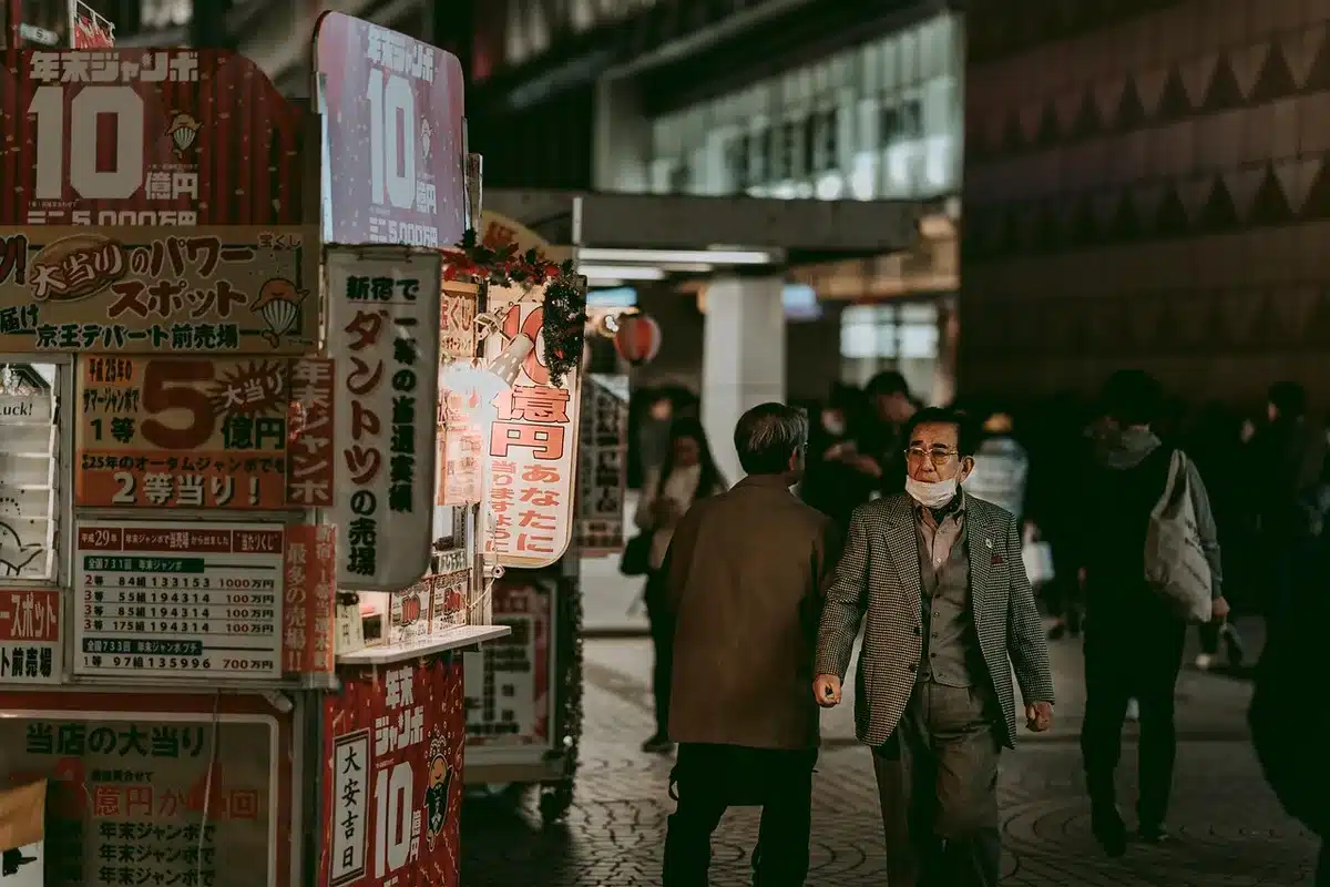 Empty neon-lit city street at night with rain-slick pavement and distant anonymous silhouettes; neon signage blurred into bokeh