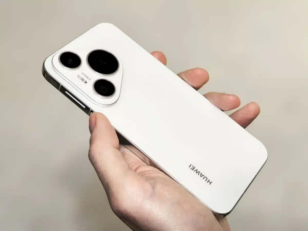 An anonymous compact smartphone on a simple table, slim profile visible, triple camera module facing up, no logos or text