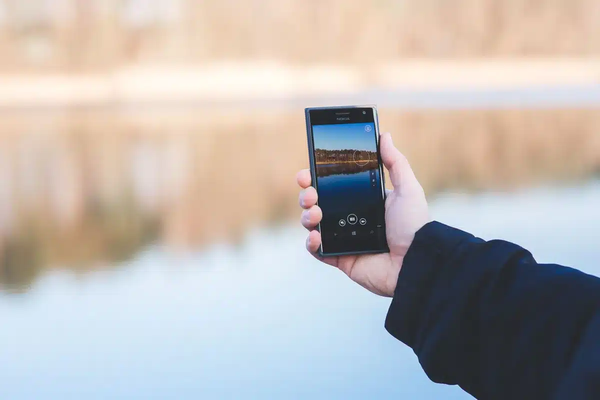 A sleek unbranded folding smartphone closed on a wooden table, soft daylight highlighting hinge detail and screen edge