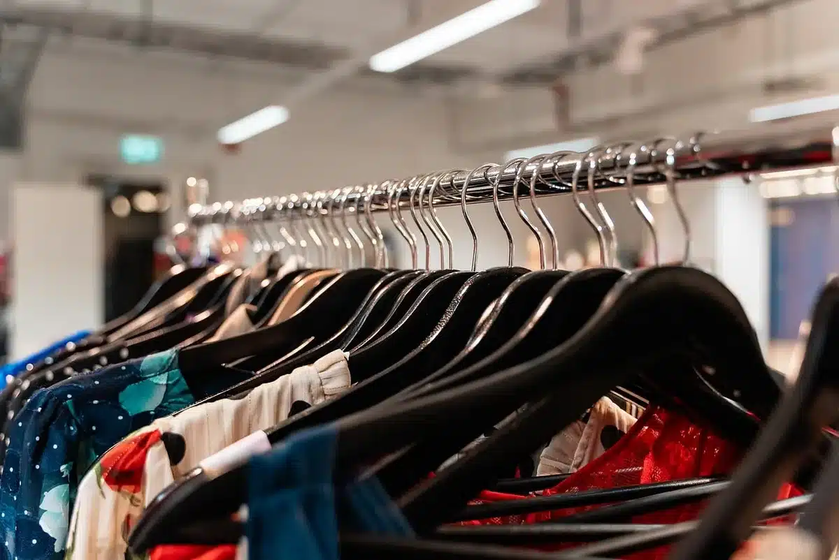Percheros con diferentes tallas en una tienda de ropa mostrando variación de stock
