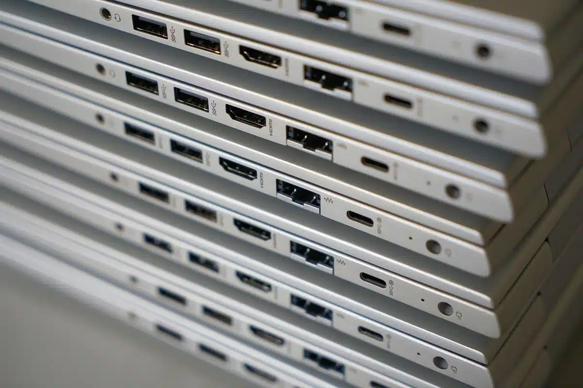 anonymous hands connecting two HDMI cables to a compact computer, neutral background, no brand