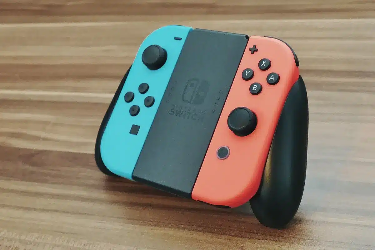 An anonymous small crowd of blurred hands holding generic game controllers under blue ambient light, a table with a turned-off phone and a headset nearby, conveying multiplayer gaming anticipation