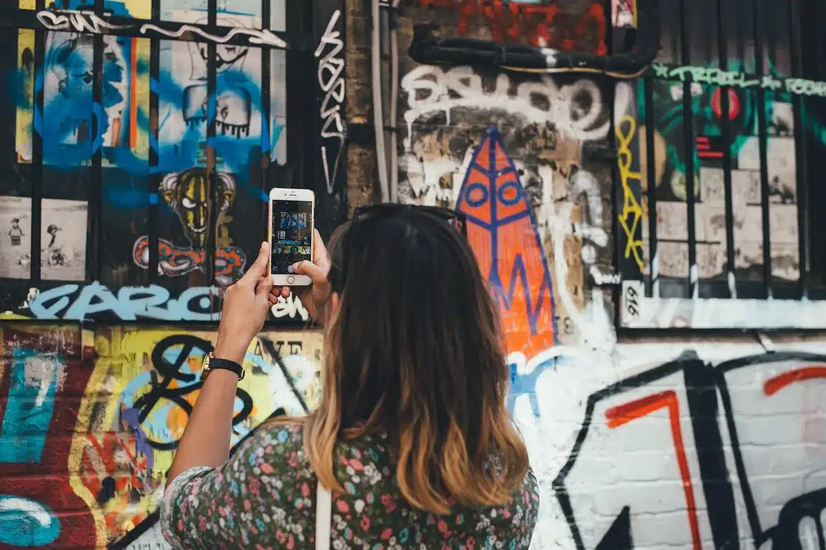 anonymous person holding a mid-range smartphone photographing a city street at golden hour, no brand visible