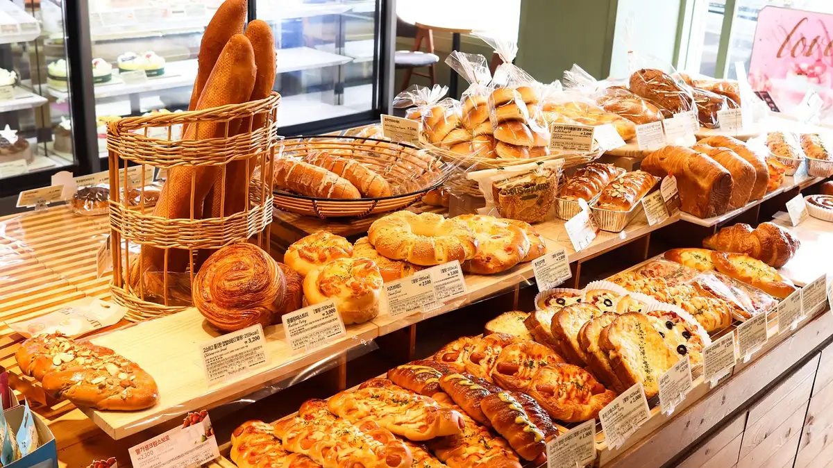 empty bakery shelf with assorted plain breads and a small unlabeled tray of round sweet rolls