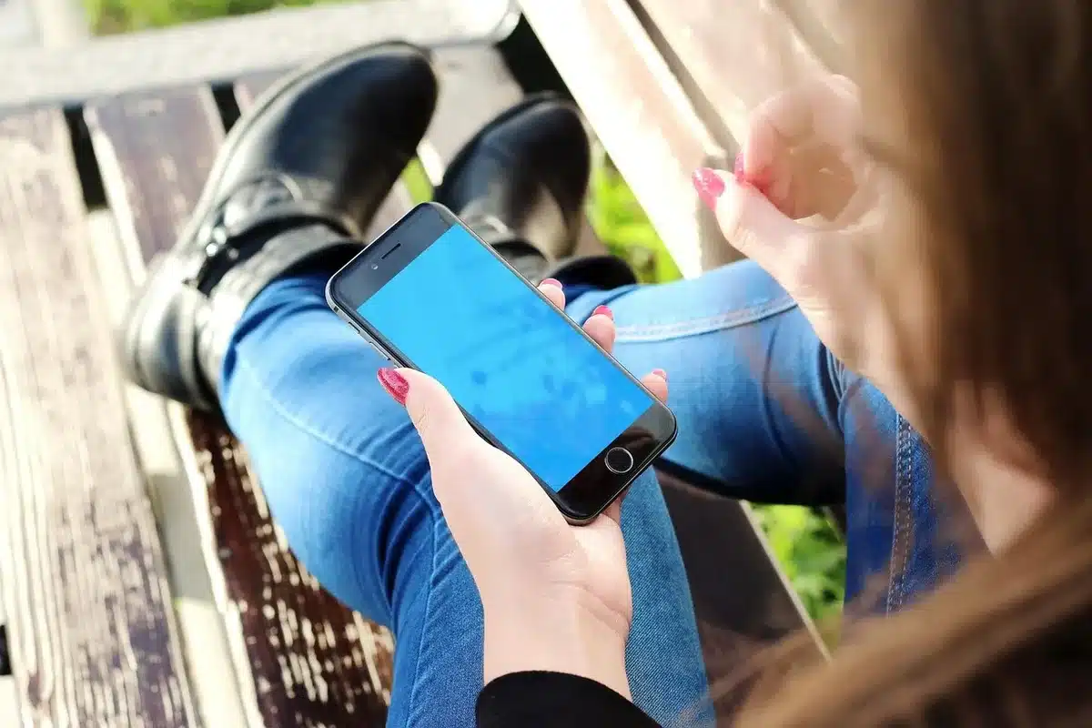 A closed luxury-style foldable phone on a soft fabric surface, gold hinge and deep blue back visible, no logos
