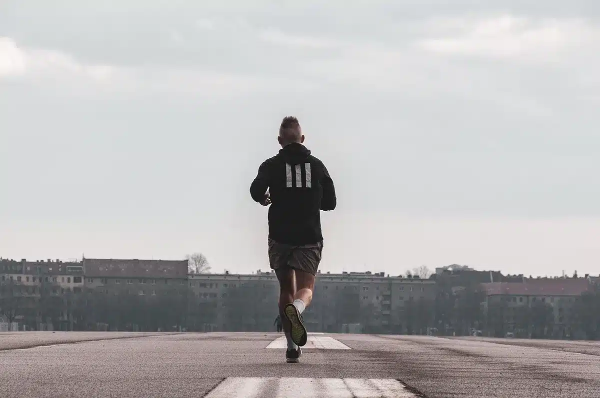 Anonymous runner adjusting clip-style earbuds near a gym bag, no brands visible