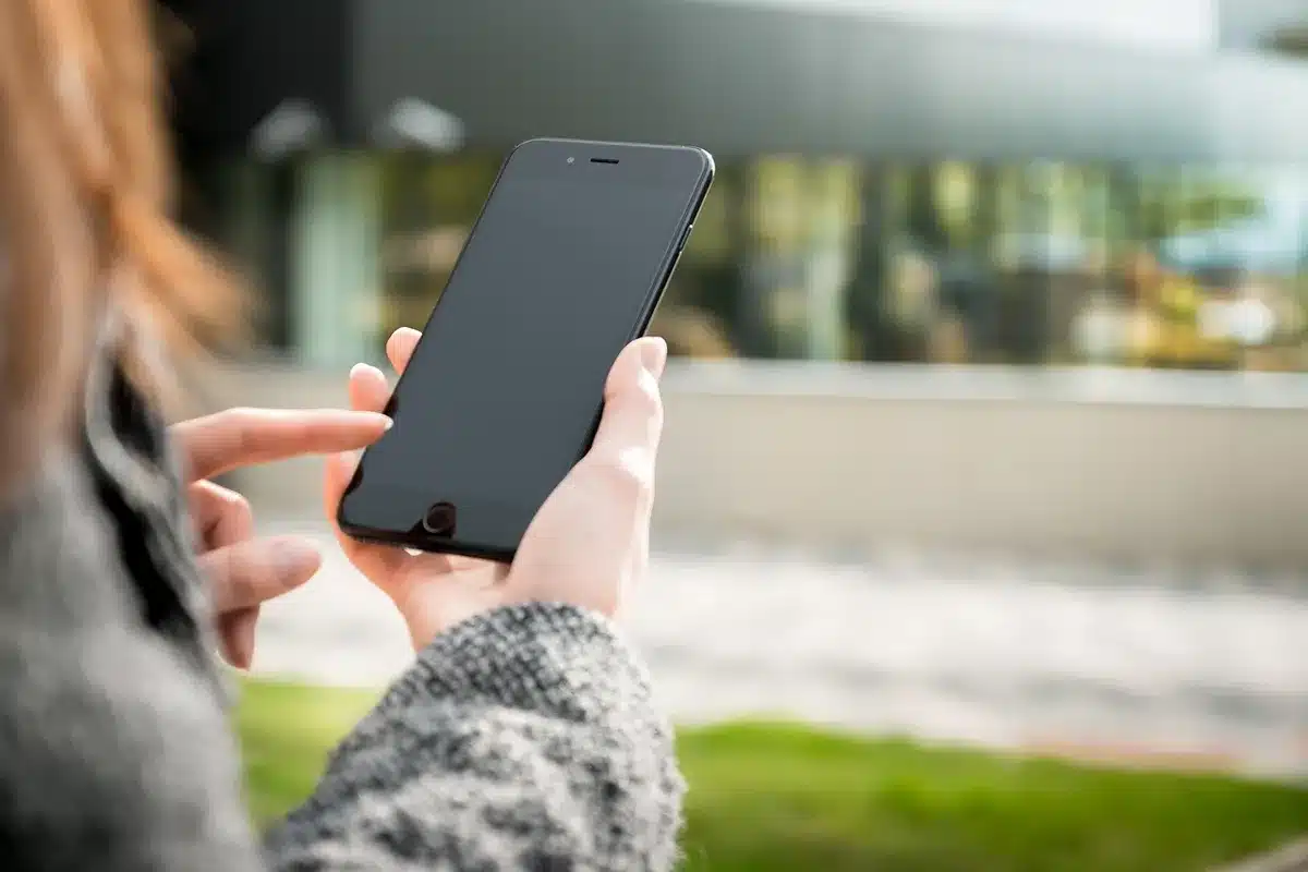 empty smartphone on a table showing a blank white game screen, anonymous hands nearby